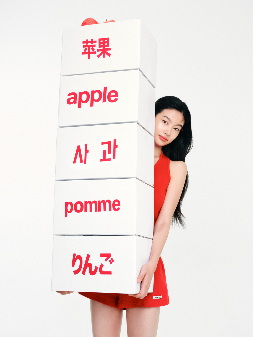 Model holding a stack of boxes reading apple in five languages